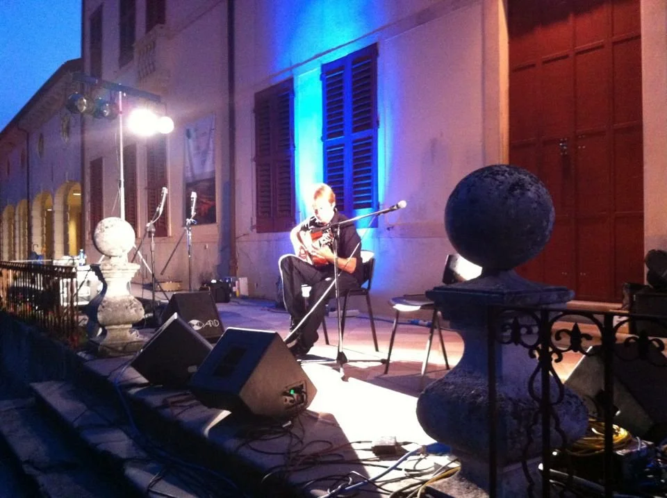 Simon Fox playing outdoors at night at a guitar festival in Northern Italy
